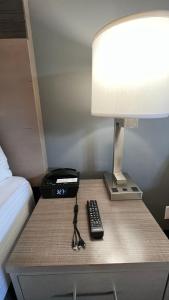 a bedside table with a lamp and a remote control at Pacific Motor Inn in San Jose