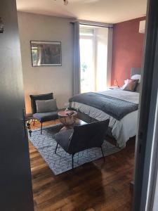 a bedroom with a bed and two chairs and a window at Chambres d'hôtes L'âme de Travassac in Donzenac