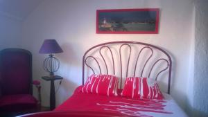 Una cama roja con almohadas rojas encima. en Maison proche plages, tous commerces, en Arzon