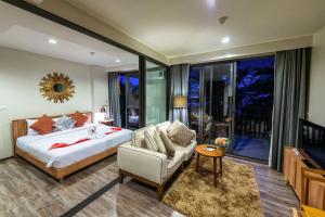 um quarto com uma cama, um sofá e uma TV em The Deck Patong by VIP em Patong Beach