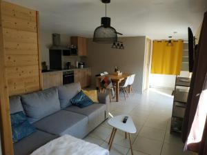 ein Wohnzimmer mit einem blauen Sofa und einem Tisch in der Unterkunft Maison d'hôtes des Bassins d'Oche in Saint-Paul-en-Chablais