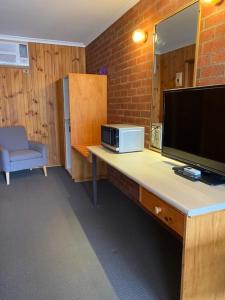a room with a desk with a television and a mirror at Country Roads in Peak Hill