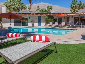 uma piscina com duas espreguiçadeiras e um guarda-sol em Hidden Haven em Palm Springs