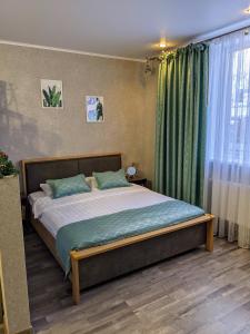 a bedroom with a large bed with green curtains at Студия #9 в Гранд Шале на Банном in Zelenaya Polyana