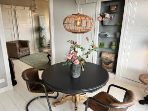 a dining room table with a vase of flowers on it at Villa Rose in Bergum