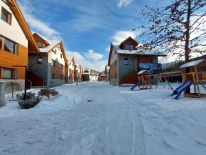 eine schneebedeckte Straße mit Häusern und einem Spielplatz in der Unterkunft Mýto Apartments BERGMAX, Ski Jasná Chopok 10min transit - Resort Mýto Apartments, parking free in Mýto pod Ďumbierom