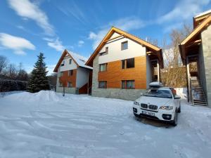 ein weißes Auto im Schnee vor einem Haus geparkt in der Unterkunft Mýto Apartments BERGMAX, Ski Jasná Chopok 10min transit - Resort Mýto Apartments, parking free in Mýto pod Ďumbierom