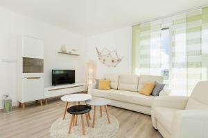 ein weißes Wohnzimmer mit einem weißen Sofa und Tischen in der Unterkunft Apartament Clara na klifie in Rewal