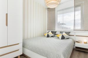 ein Schlafzimmer mit einem Bett mit Kissen und einem Fenster in der Unterkunft Apartament Clara na klifie in Rewal