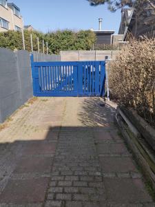 a blue gate on the side of a sidewalk at zilvermeeuw in Bergen aan Zee