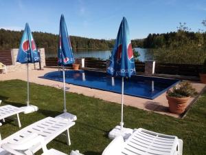 a group of chairs and umbrellas next to a pool at Penzion Ratmírák in Malý Ratmírov