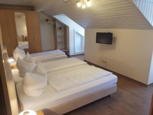 1 dormitorio con 2 camas blancas y TV en La Locanda Ristorante Pizzeria Garni, en Ohlstadt