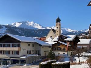 uma aldeia com uma igreja e montanhas cobertas de neve em Ferienwohnung Dorfzentrum em Disentis
