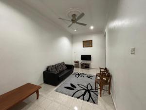 ein Wohnzimmer mit einem schwarzen Sofa und einem TV in der Unterkunft Homestay Bidor DMaju in Bidur