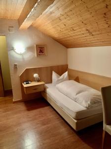a bed in a room with a wooden ceiling at La Locanda Ristorante Pizzeria Garni in Ohlstadt +111 photos