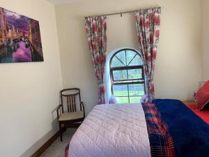 a bedroom with a bed and a window and a chair at Cut Limestone Apartment Riverside Lodge in Carlow