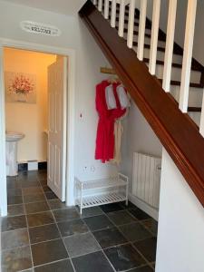 a hallway with a staircase and a red shirt hanging on the wall at Cut Limestone Apartment Riverside Lodge in Carlow