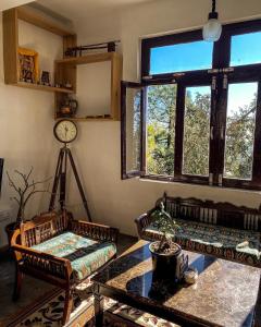 een woonkamer met stoelen en een tafel en ramen bij Redeem Cafe & Homestay in McLeod Ganj