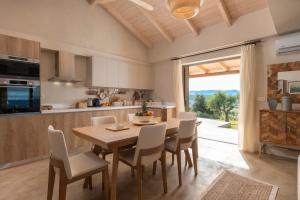 kuchnia i jadalnia z drewnianym stołem i krzesłami w obiekcie Villa Carvella - A Sublimely Relaxing Escape! w mieście Tsilivi
