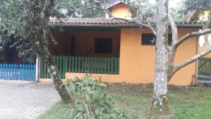 een huis met een blauw hek ervoor bij Alegria casa 3 dorms Cond Fechado churrasqueira piscina in Boicucanga