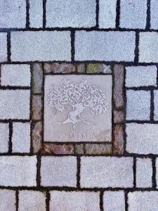 a metal plaque with a tree on a brick sidewalk at Pizzo Casale in Vico del Gargano