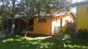 una pequeña casa amarilla con escaleras y un patio en Alegria casa 3 dorms Cond Fechado churrasqueira piscina, en Boicucanga