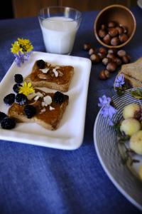two pieces of toast with blackberries and flowers on a plate at Sapigno B&B in SantʼAgata Feltria