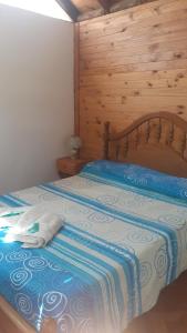 een slaapkamer met een bed met een houten muur bij Cabañas El Abuelo Alfredo in Ciudad Lujan de Cuyo