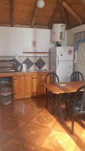 a kitchen with a wooden table and a table and a refrigerator at Cabañas El Abuelo Alfredo in Ciudad Lujan de Cuyo