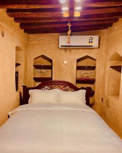1 dormitorio con 1 cama grande con almohadas blancas en Jawharat Alaqar Inn نزل جوهرة العقر, en Nizwa