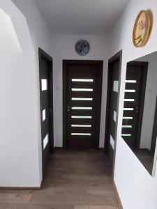 a hallway with two doors and a clock on the wall at Dabe Hd in Hunedoara