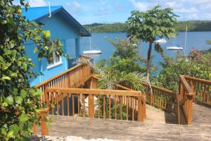 a blue house with a wooden deck next to the water at Boathouse Apartments in Neiafu