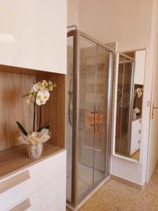 uma cabina de duche em vidro numa casa de banho com um vaso de flores em La locanda di Gioele em Lido di Camaiore