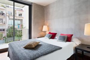 Un dormitorio con una cama blanca con almohadas rojas y una ventana en My Space Barcelona Executive Apartments Center en Barcelona