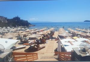 a beach with many umbrellas and people in the water at Villa Nickolas in Paleo Tsifliki