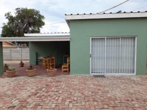 une maison verte avec une terrasse et une porte dans l'établissement 7 On Strauss, à Beaufort West