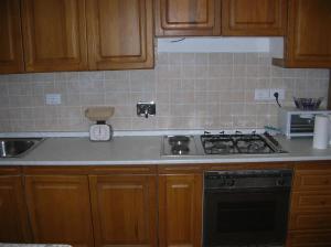 a kitchen with wooden cabinets and a stove top oven at Appartamento orlando vista panoramica Pomonte isola D'Elba in Pomonte