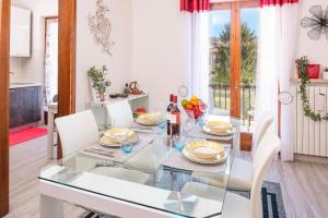 een eetkamer met een glazen tafel en witte stoelen bij CASA POPPEA in Bardolino