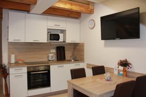 a kitchen with white cabinets and a table and a tv at Apartments Borna 2 in Zagreb