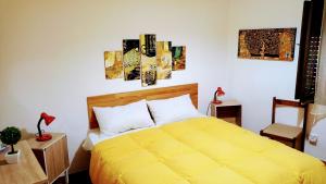 a bedroom with a yellow bed and paintings on the wall at La casa di Maya in Sassari