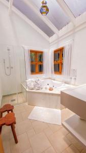 a white bathroom with a tub and a shower at Pousada O Cantinho da Raposa in Monte Verde