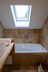 baño con bañera y ventana en Domaine des Pousses, Chambres d'hôtes au coeur d'un village de campagne en Droue-sur-Drouette