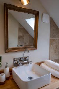 a bathroom with a white sink and a mirror at Domaine des Pousses, Chambres d'hôtes au coeur d'un village de campagne in Droue-sur-Drouette