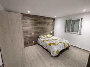 een slaapkamer met een bed en een houten muur bij Villa Ô Bel Air - 4 étoiles - détente au bord de la piscine et baby-foot ! in Saint-Joseph