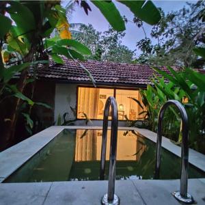 una piscina con dos mangos metálicos frente a una casa en Sunsets and Palm Trees, en Alleppey