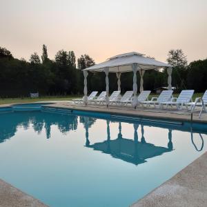 uma piscina com cadeiras brancas e um gazebo em Paraíso Liumalla Lodge em Villarrica