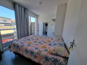 a bedroom with a bed and a large window at PRAIA DOS ANJOS - SUÍTEs in Arraial do Cabo