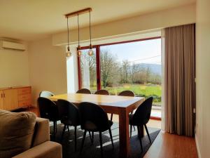 uma sala de jantar com mesa e cadeiras e uma grande janela em Casa de Penedones - Ventos do Larouco em Penedones