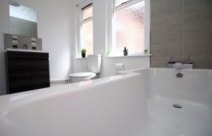 a white bathroom with a tub and a toilet at Empire House by Tŷ SA in Newport