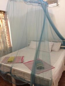 Schlafzimmer mit einem Bett mit Moskitonetz in der Unterkunft Guesthouse Kind and Love in Hikkaduwa